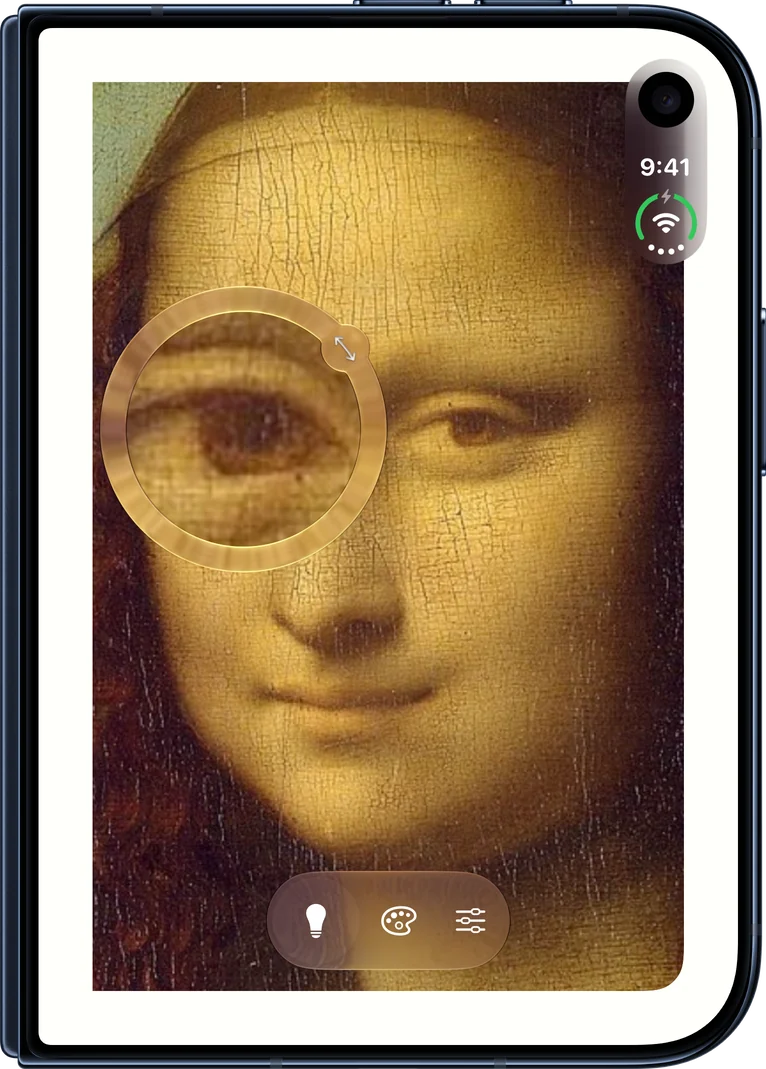 Compact บน iPhone Duo ที่ปิดอยู่: ภาพ Mona Lisa ในกระจกที่มีวงแหวนแสงล้อมรอบ พร้อมแว่นขยายที่ดวงตาซ้ายของเธอ และแคปซูลควบคุมอยู่ใต้ใบหน้า